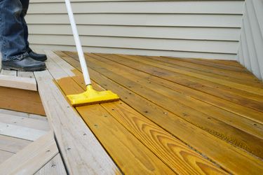 A finely stained back yard deck with a fence.